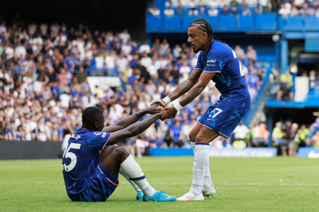 Malo Gusto helps Moises Caicedo of Chelsea to his feet during the Premier League match between Chelsea FC and Manchester City FC at Stamford Bridge...