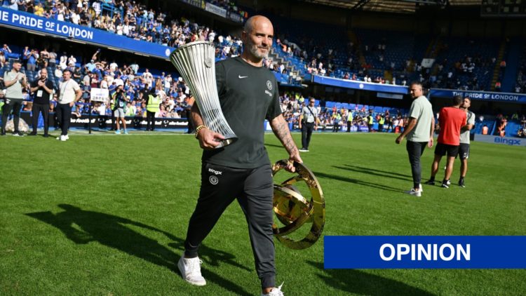 Chelsea boss Enzo Maresca carries the Conference League and Club World Cup trophies on the pitch at Stamford Bridge