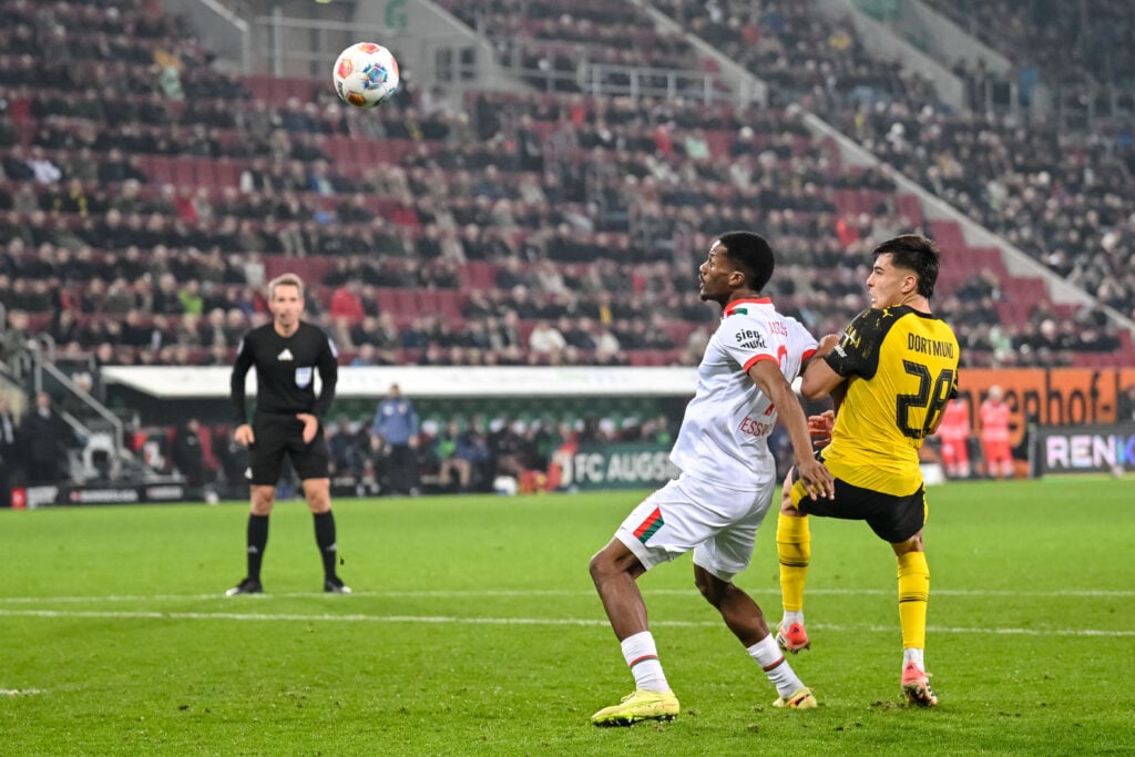 Samuel Essende of Augsburg and Aaron Anselmino of Borussia Dortmund battle for the ball during the Bundesliga match.